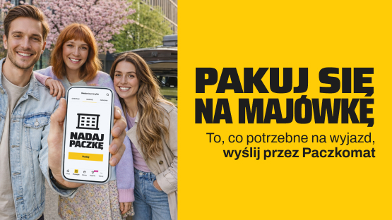 Uśmiechnięte dwie dziewczyny i chłopak, który trzyma w ręce telefon. W tle zapakowany bagażami samochód. 
