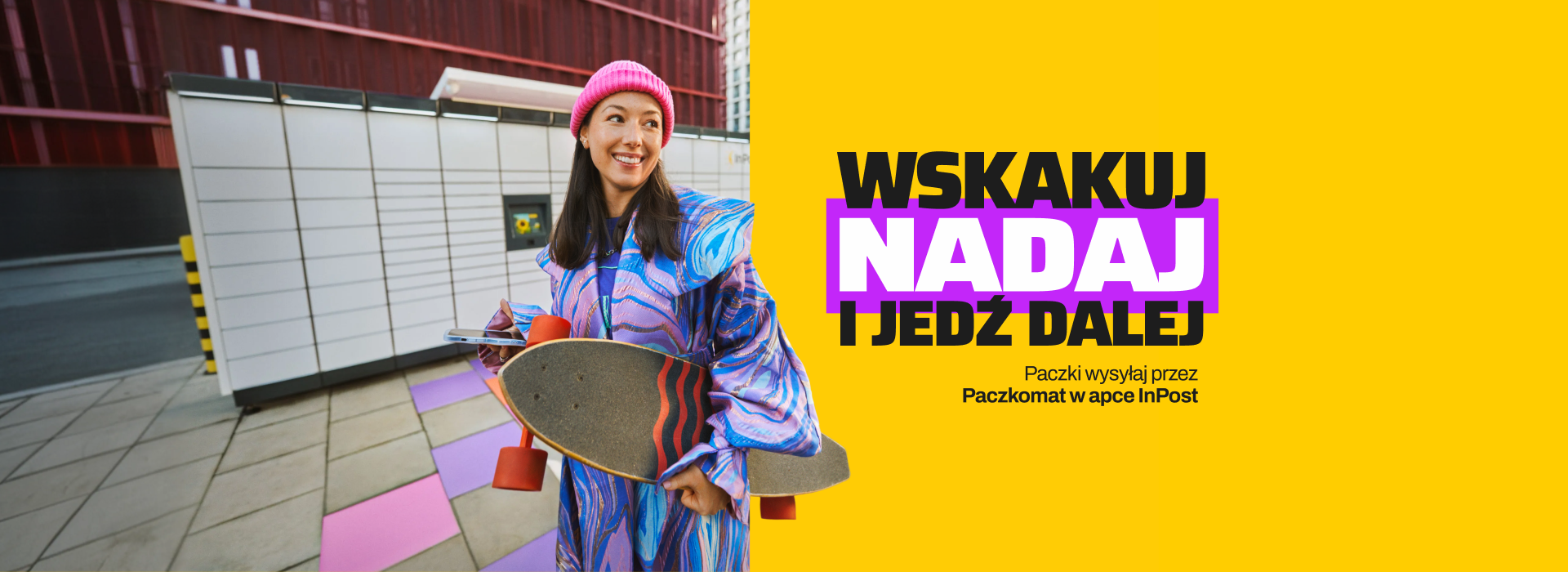 Uśmiechnięta dziewczyna z deskorolka pod pachą i telefonem w ręce. W tle Paczkomat.